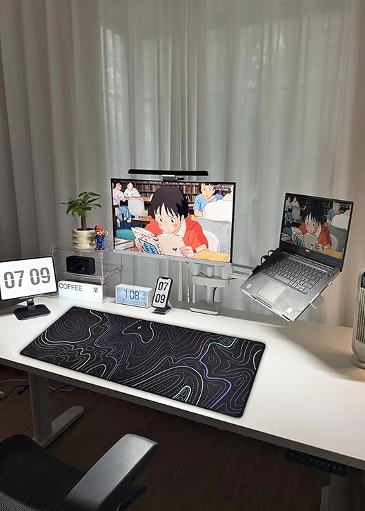Large extended gaming mouse pad with topographic map design on white standing desk setup with monitor and laptop