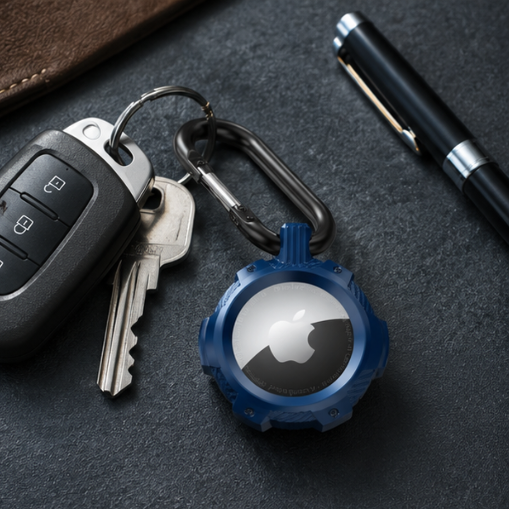 Apple AirTag in a dark blue carabiner keychain holder attached to a set of car keys, placed on a dark surface alongside a pen and wallet
