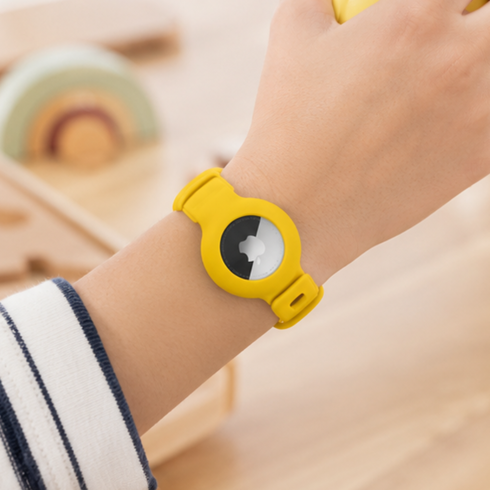 Child wearing a yellow silicone Apple AirTag wristband on their wrist, designed as a kids safety tracker band, shown in a close-up lifestyle shot