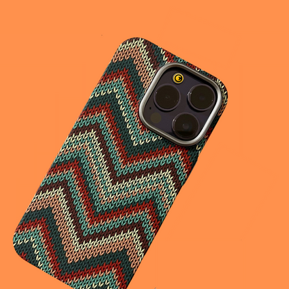 Close-up of the Award Night Light iPhone Cover, highlighting the distinctive colorful braided chevron texture and camera lens protection on an orange background.
