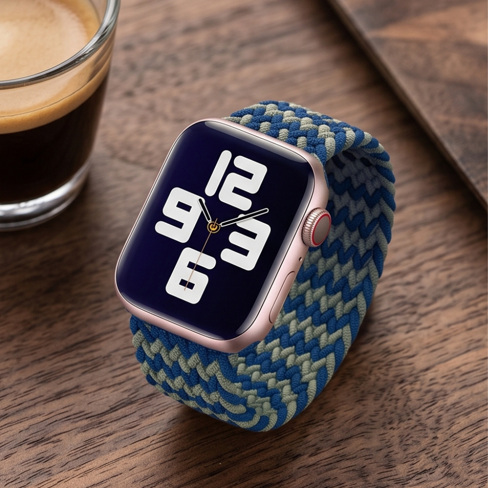 Apple Watch with a blue and yellow chevron patterned braided solo loop band displayed on a dark surface, showing the watch face at a slight angle