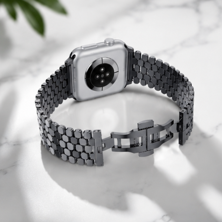 Apple Watch with silver stainless steel jubilee link band laid flat on a white marble surface with soft natural lighting