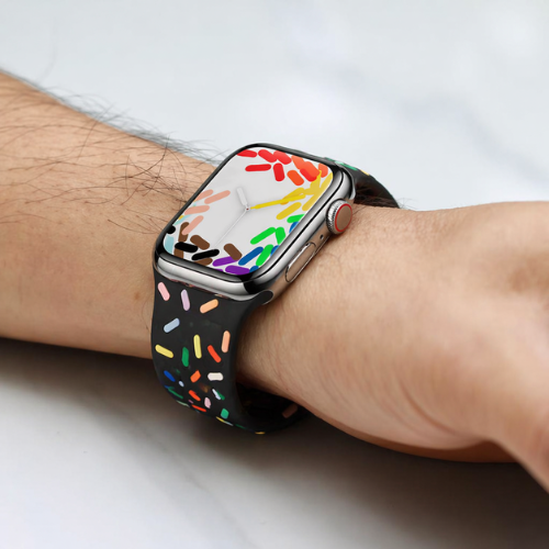 Colorful silicone smartwatch band with multi-color geometric pattern design, worn casually on wrist in outdoor setting