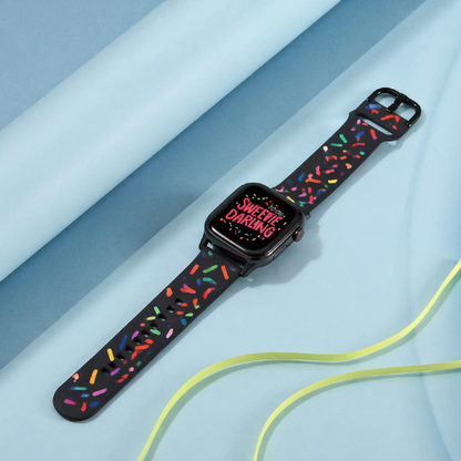 Colorful silicone smartwatch band in light blue tone with decorative pattern, worn on wrist against sky background, showing comfortable fit