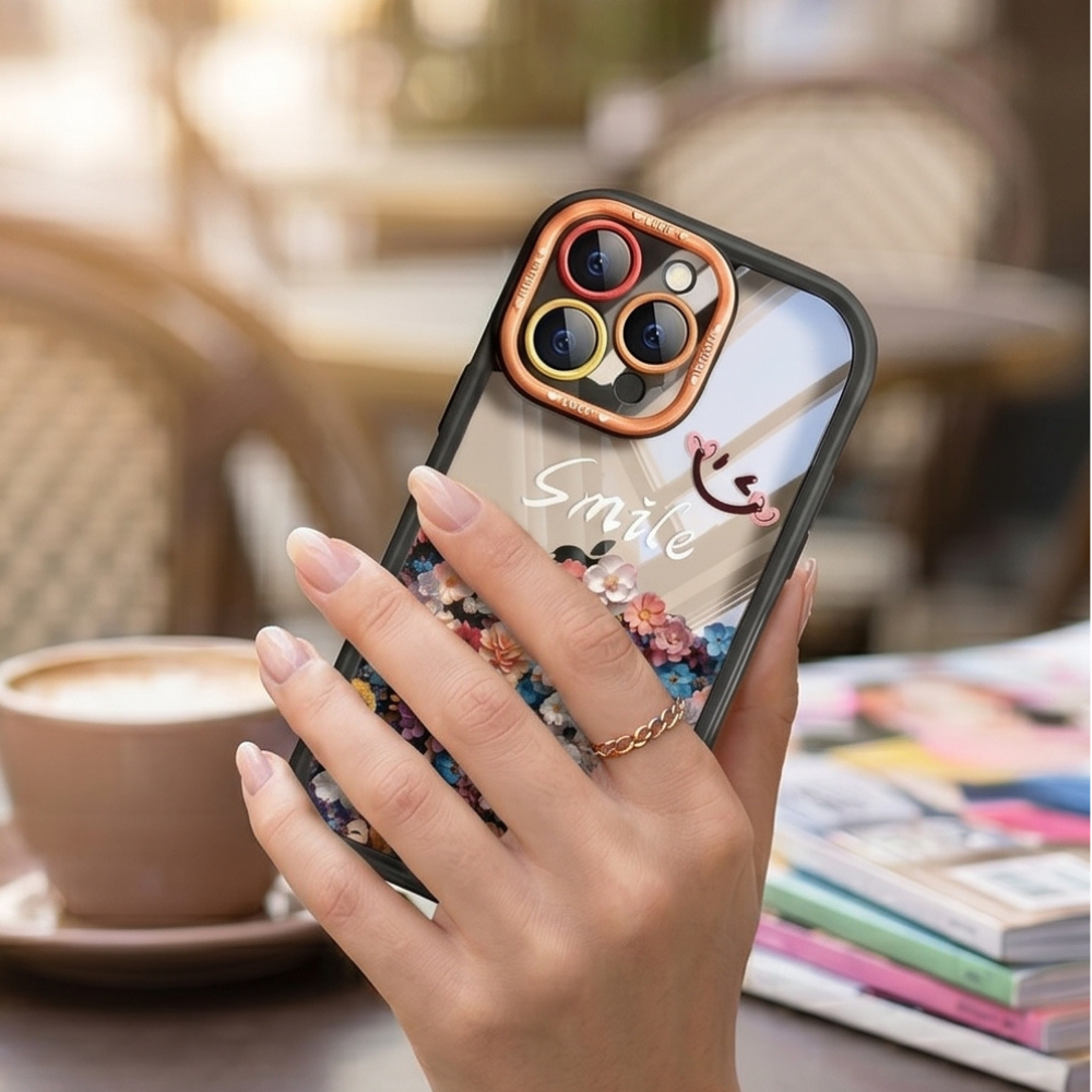 Floral iPhone case with colorful flower design and rose gold camera ring held in hand at café, showcasing protective lens frame