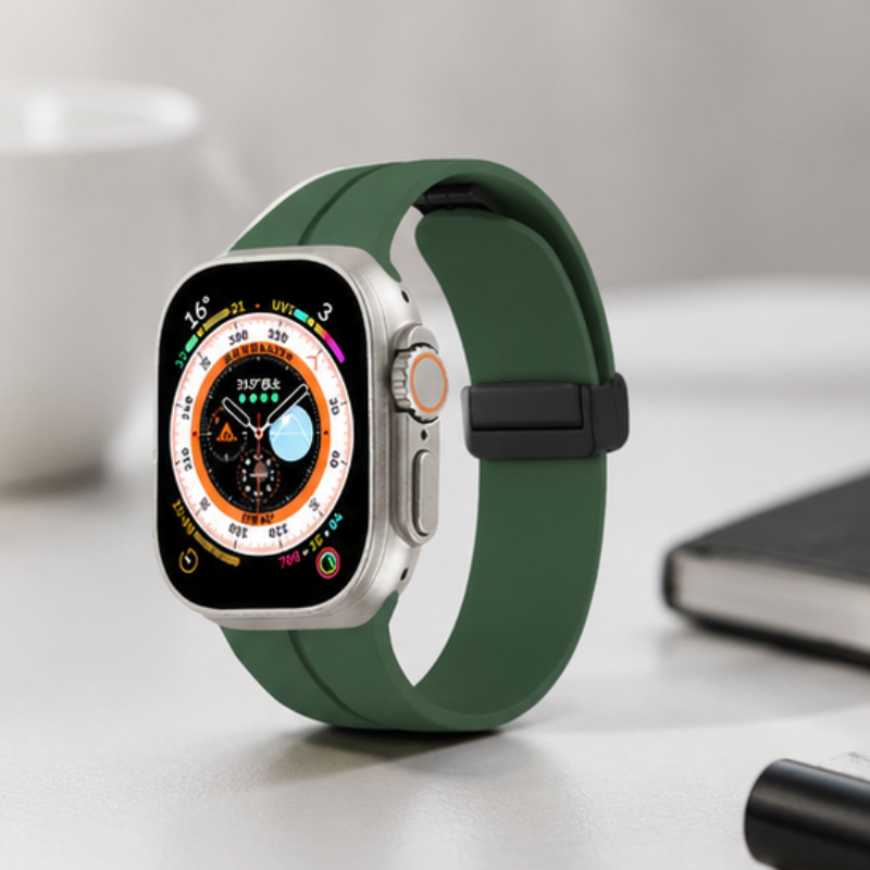 Apple Watch Ultra with forest green silicone sport band displayed on a white desk beside a charging cable