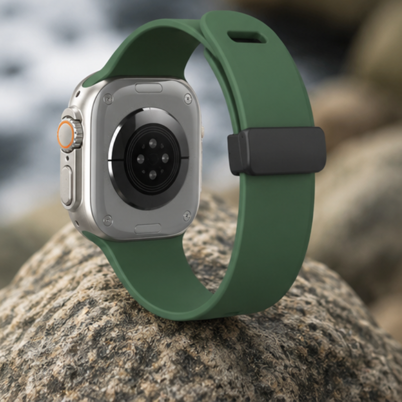 Apple Watch Ultra with forest green silicone sport band resting on a rock outdoors, showing the compass watch face
