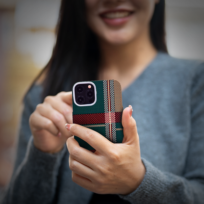 A woman displays her iPhone 16 with a green and red plaid case, showcasing style and functionality.