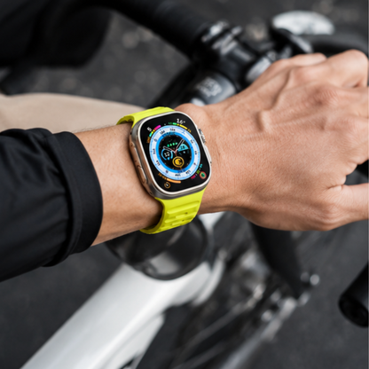 Person wearing Apple Watch Ultra with neon yellow silicone sport band while gripping motorcycle handlebars