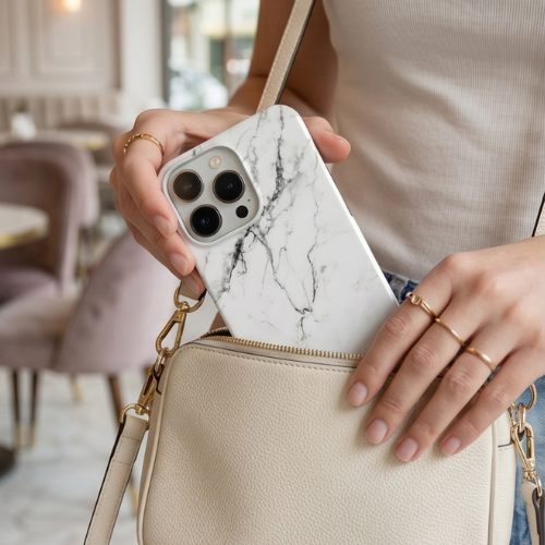 Woman holding a white marble-patterned iPhone case with a beige crossbody bag | GrunX