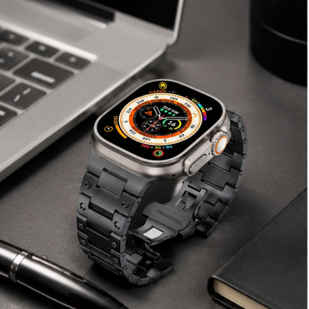 Top Left:Apple Watch Ultra with black stainless steel link band placed on a dark notebook beside a pen and laptop