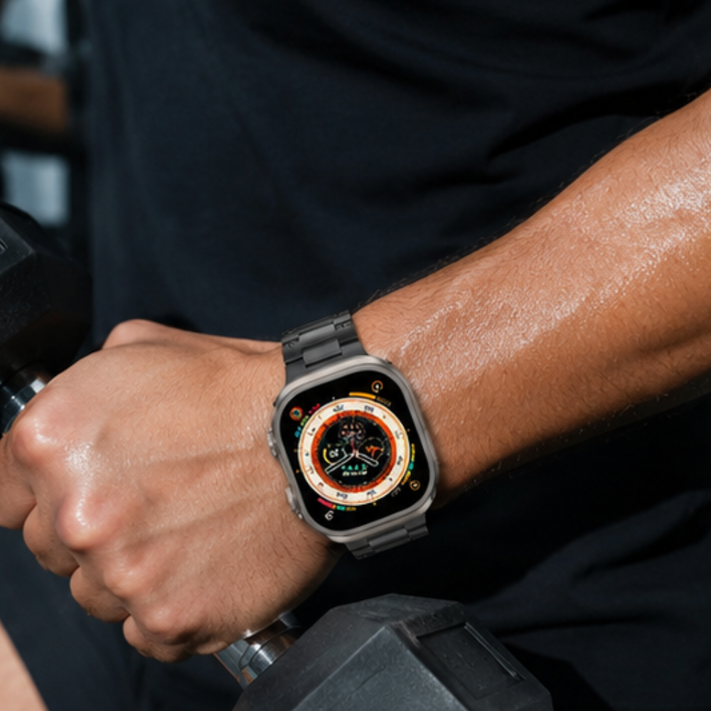 Person wearing Apple Watch Ultra with black metal link band while gripping a dumbbell at the gym