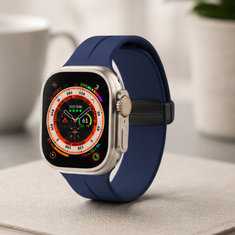 Angled front view of Apple Watch Ultra with navy blue silicone sport band displaying an orange compass watch face, placed on a white surface