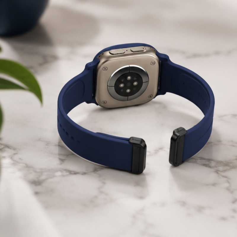 Rear view of Apple Watch Ultra with navy blue silicone sport band on a white background, showing back sensors and band attachment
