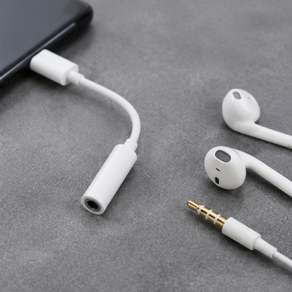 White USB-C to 3.5mm audio adapter displayed with wired earbuds on dark background