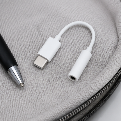 White USB-C to 3.5mm audio adapter placed on a grey fabric pouch