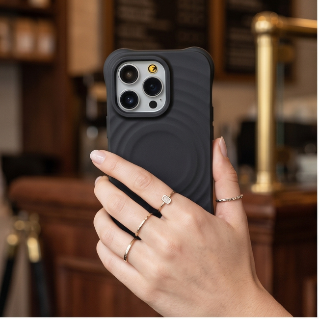 Hand holding a black rugged iPhone case in a library setting