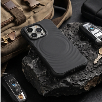Black rugged iPhone case placed on a rock alongside car keys and tactical gear