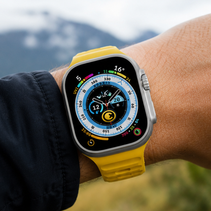 Apple Watch Ultra with bright yellow rubber sport band worn on a wrist against a blurred mountain landscape background